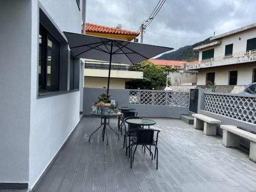 a patio with a table and chairs and an umbrella at Caniçal houses - Madeira in Caniçal