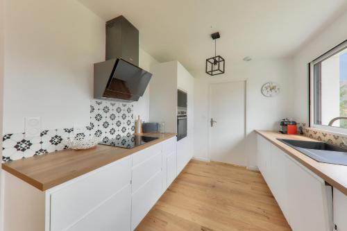 a kitchen with white cabinets and a sink at Maison neuve pour 8, 800m des plages in Le Tour-du-Parc