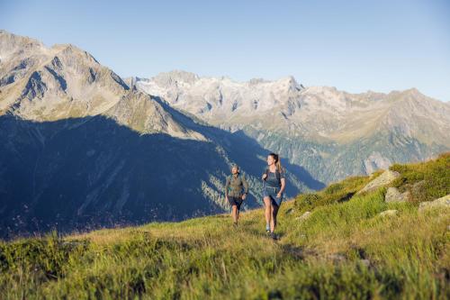 two people walking on a mountain with mountains in the background at PACHMAIR 1453 apart resort in Uderns