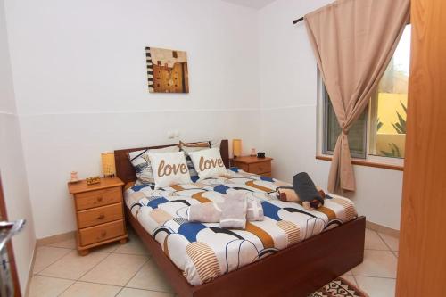 a bedroom with a bed with love pillows and a window at Casa Irma in Santa Maria