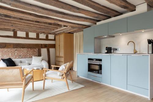 une cuisine avec des armoires bleues et un salon dans l'établissement Pick A Flat's Apartments in Saint Louis - Quai des Orfèvres, à Paris