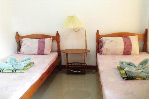 two beds in a room with a lamp and a table at Citadel Bed and Breakfast in Puerto Princesa City