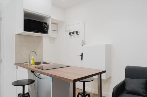 - une cuisine avec une table, un évier et un four micro-ondes dans l'établissement Studio Granier sud, à Chambéry