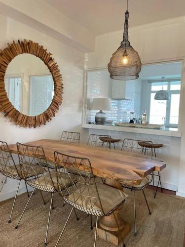 a dining room table with chairs and a mirror at Casa da Praia em Soltroia Mar in Comporta