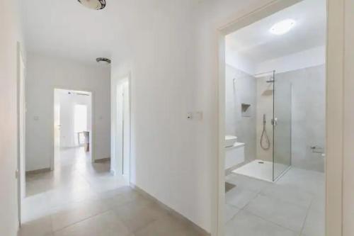 a white bathroom with a walk in shower and a mirror at Villa La Domazet in Podstrana