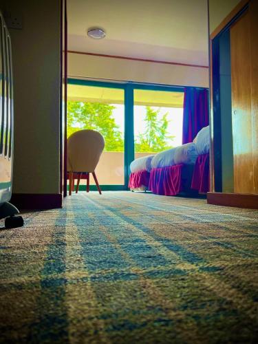 a room with two beds and a chair and a window at Loch Ness Lodge Hotel in Drumnadrochit