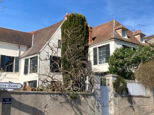 a white house with a tree on the side of it at La Villa Lauvray in Vétheuil