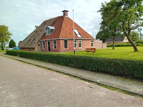 a house with a thatched roof with a bench in front at It Linestek in Niawier