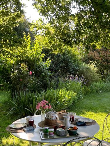 een witte tafel met eten erop in een tuin bij B&B Le bain d'Alice in Saint-Laurent-sur-Gorre