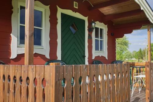 a house with a green door and a wooden fence at Ekebacken Gård & Mc-camping in Blidsberg