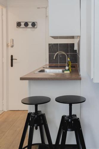 une cuisine avec deux tabourets noirs devant un évier dans l'établissement Studio L'épine, à Chambéry