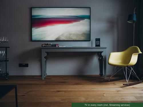 a television on a table in a room with a yellow chair at Appart Hotel Knappaboda in Lech am Arlberg