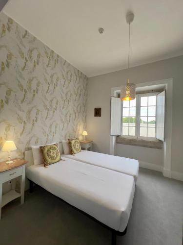 a bedroom with a large white bed and a window at Thomar House in Tomar