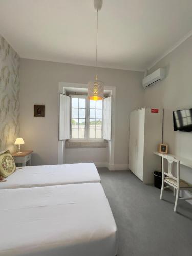 a white bedroom with two beds and a window at Thomar House in Tomar