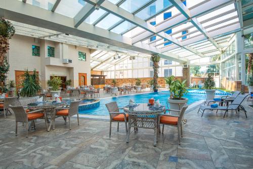 an indoor patio with tables and chairs and a pool at Bristol Hotel in Amman