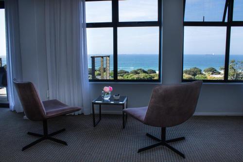 two chairs and a table in a room with windows at Ocean Vista Boutique Guest House in Durban