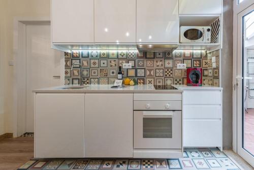 a kitchen with white cabinets and a stove at GuestReady - Cosy getaway in Porto in Bandeira