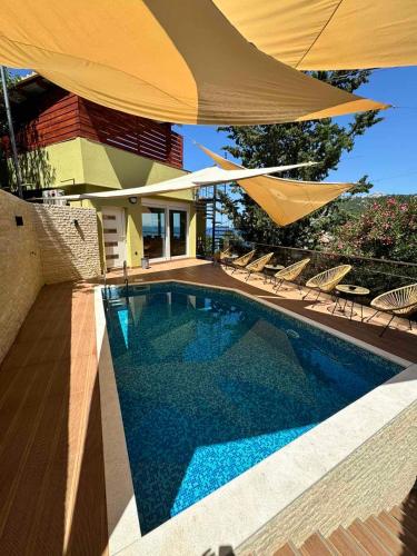 a swimming pool with a large yellow umbrella and chairs at Resort Stikovic in Dobra Voda