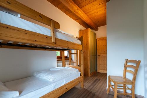 a bedroom with two bunk beds and a wooden chair at Maso Salim Relax Apartments in Drena