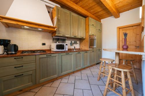 a kitchen with green cabinets and a counter with stools at Maso Salim Relax Apartments in Drena