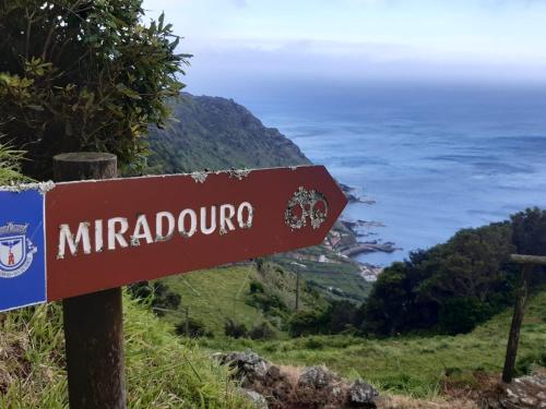 a sign on a hill with the ocean in the background at Casinha do Barreiro - Cosy Private Cottage in Vila do Porto