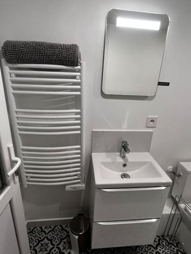 une salle de bain blanche avec un lavabo et un miroir dans l'établissement Logement proche gare et Versailles, à Marly-le-Roi
