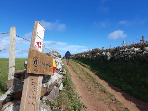 a person walking down a dirt road next to a rock wall at Casinha do Barreiro - Cosy Private Cottage in Vila do Porto
