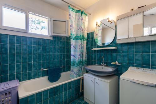 a green tiled bathroom with a sink and a tub at Appartement dans cadre de verdure in La Seyne-sur-Mer