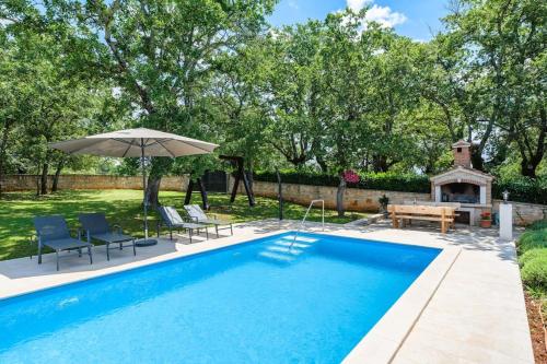 a swimming pool with chairs and an umbrella and a grill at Casa Ana Tripari by Briskva in Višnjan