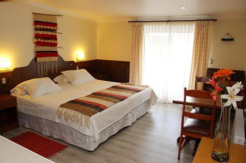 a bedroom with a bed and a desk and a window at Hotel Rucaitue in Osorno