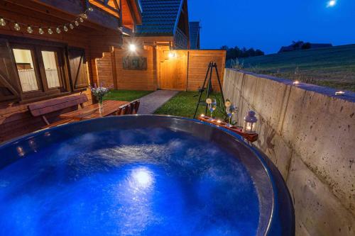 a large blue swimming pool in a backyard at night at Domki Gorczański Zakątek - Jacuzzi in Nowy Targ