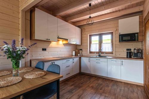 a kitchen with white cabinets and a wooden floor at Domki Gorczański Zakątek - Jacuzzi in Nowy Targ