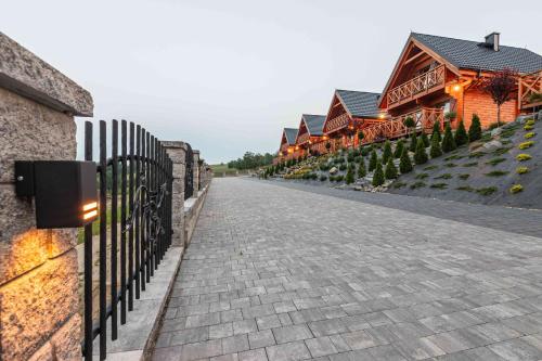 a cobblestone street with a fence and a building at Domki Gorczański Zakątek - Jacuzzi in Nowy Targ