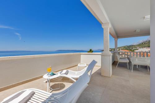 a balcony with white chairs and a view of the ocean at Hotel Laurentum in Tučepi