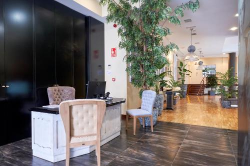 a waiting room with chairs and a desk and plants at Hotel AR Isabel de Farnesio in La Granja de San Ildefonso