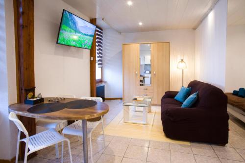 un salon avec un canapé et une télévision au mur dans l'établissement L'Eden, studio loft zen, à Ensisheim