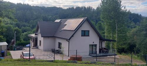 a white house with solar panels on the roof at WILLA NA WYŁĄCZNOŚĆ 12 os BIESZCZADY z Salą Imprezową, Jacuzzi, Sauną, Balią Zewnętrzną oraz 2 baseny z podgrzewaną wodą - Rezydencja Matiaszówka in Polańczyk