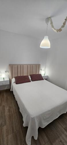 a bedroom with a large white bed with a lamp at Vitarka, ático del mar in Torre del Mar