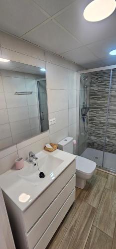 a bathroom with a sink and a toilet and a mirror at Vitarka, ático del mar in Torre del Mar