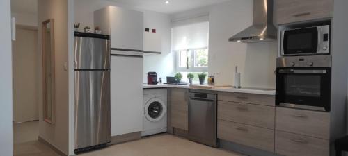 eine Küche mit einem Kühlschrank, einer Waschmaschine und einem Trockner in der Unterkunft Chez Camille appartement spacieux 75m2 climatisation wifi parking terrasse et cour privative a 50 m de la plage in Le Grau-du-Roi