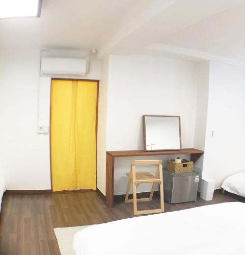 a yellow door in a room with a desk at Eoulim Guesthouse 2 in Andong