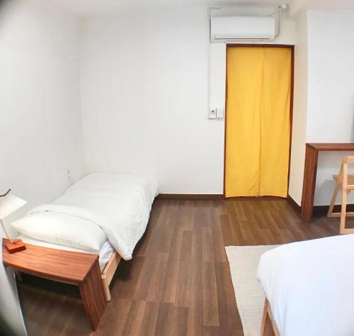 a room with two beds and a yellow door at Eoulim Guesthouse 2 in Andong