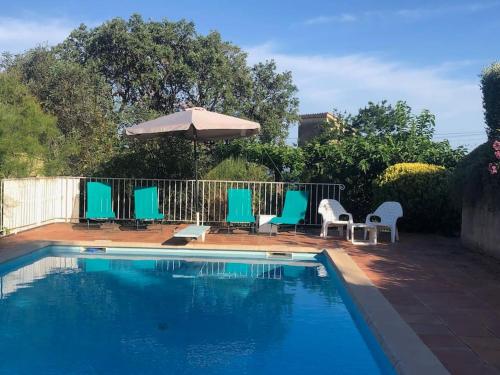 - une piscine avec des chaises bleues et un parasol dans l'établissement Villa avec piscine, à Fréjus