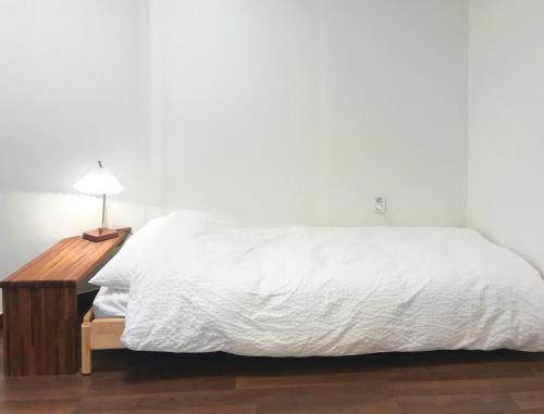 a bedroom with a white bed with a night stand and a lamp at Eoulim Guesthouse 2 in Andong