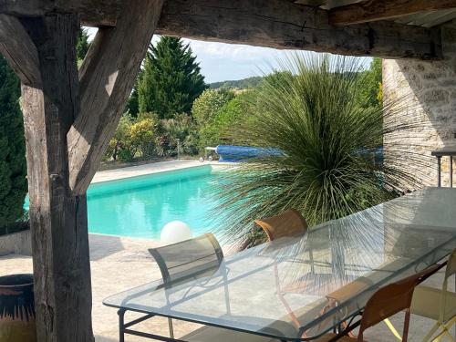 une table et des chaises en verre à côté de la piscine dans l'établissement Maison de campagne 5 chambres, à Foulayronnes