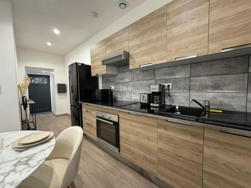 une cuisine avec des armoires en bois et un réfrigérateur noir dans l'établissement Joli Appartement Saint-germain, à Saint-Germain-au-Mont-dʼOr