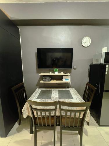 mesa con sillas y TV en una habitación en Field Residences -1 bedroom Comfort Inn, en Manila