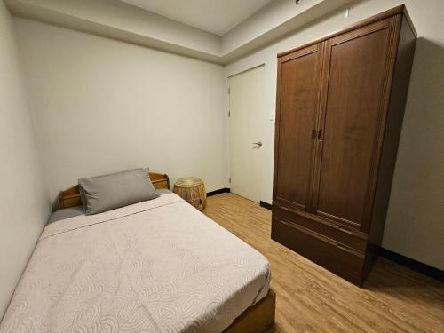 a bedroom with a bed and a wooden cabinet at Verdon Parc 2 Bedroom with 2 Balcony in Davao City