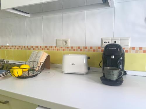 a kitchen counter with a coffee maker and a basket of fruit at FuensalidaHomes201 in Fuensalida