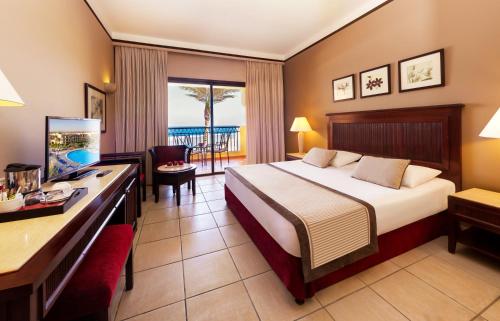 a hotel room with a bed and a desk at JAZ Lamaya Resort in Coraya Bay